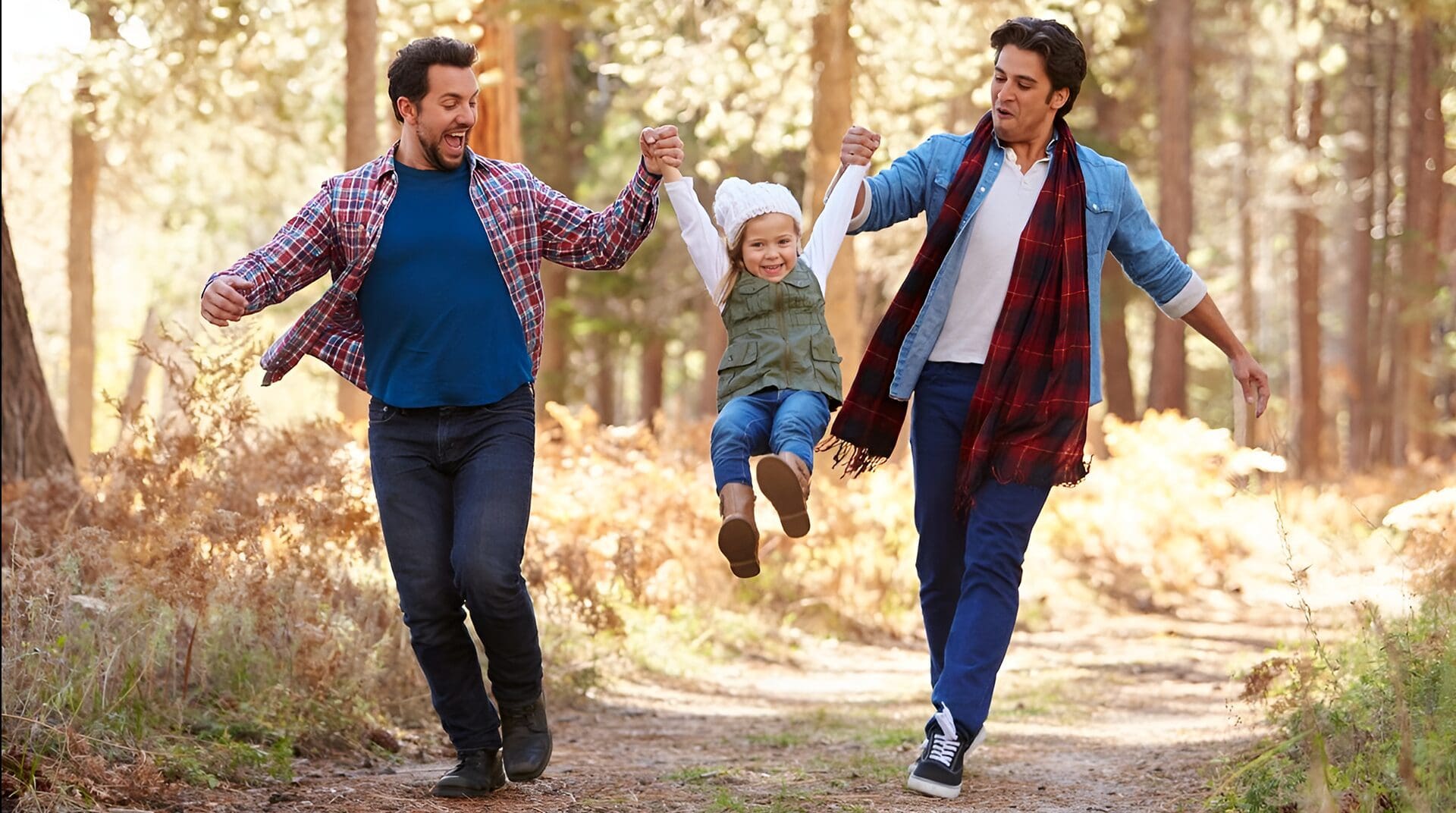 Two dads and a child in forest.